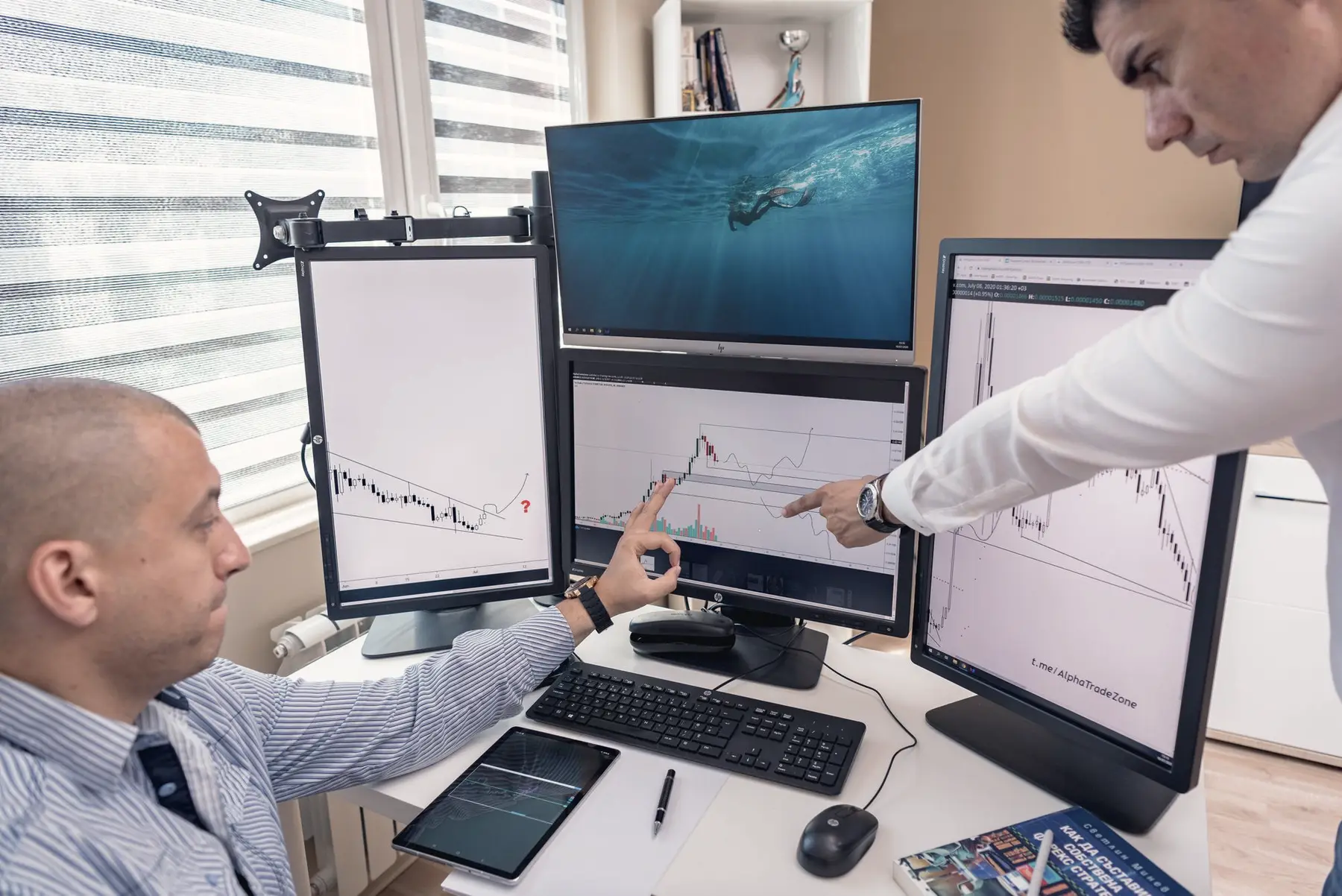 Two colleagues working through plans across several monitors