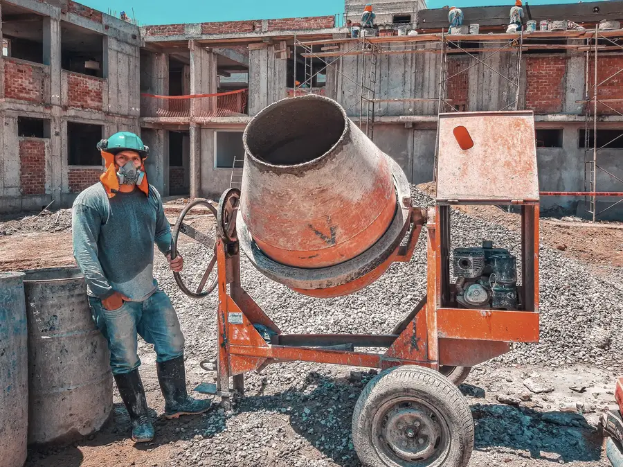 A site worker in a hard hat and protective clothing operating plant